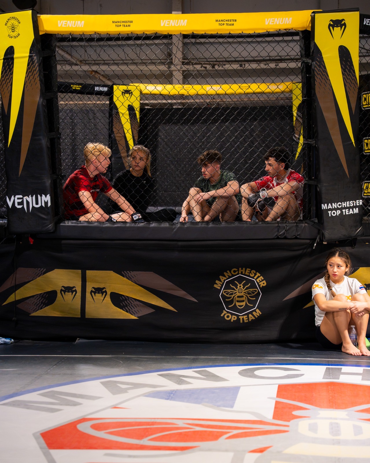 Fight team sitting on the cage apron at Manchester Top Team